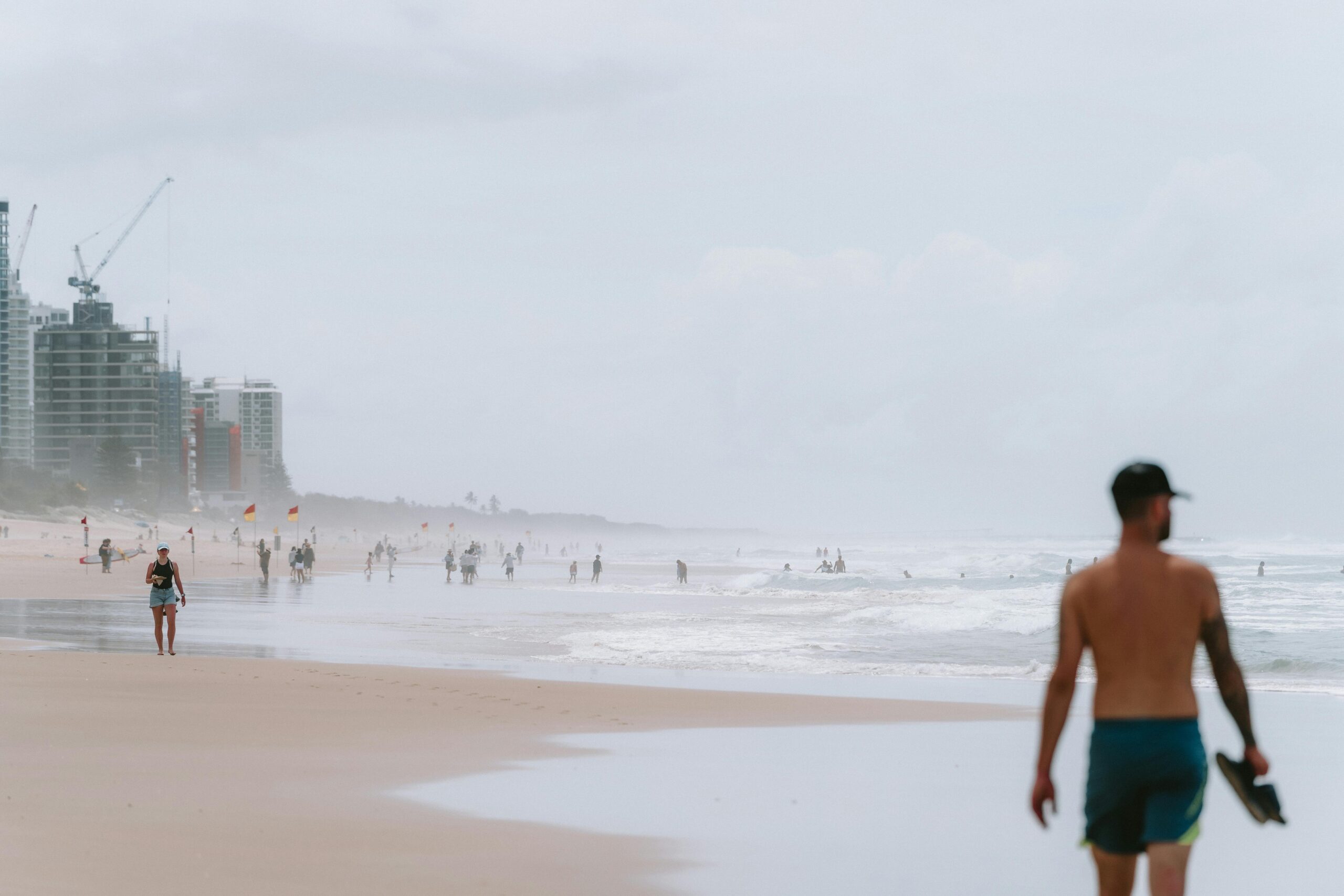 Beachgoers enjoy the sandy shores of Surfer's Paradise, Queensland, under cloudy skies.
