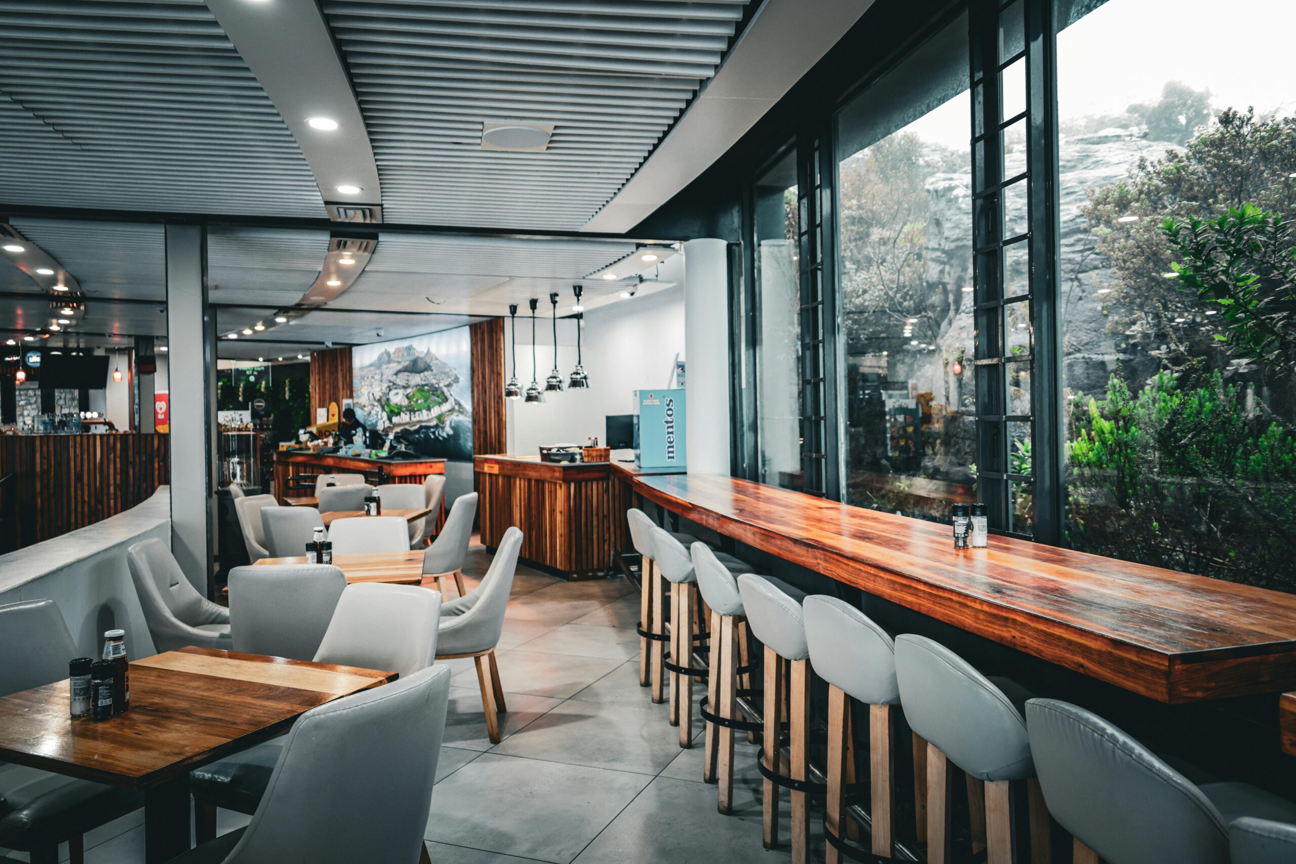 Cozy and modern restaurant interior with wooden furniture and large windows.