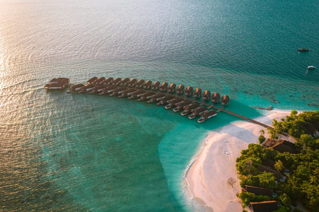 Stunning aerial shot of Kudafushi Island Resort with turquoise waters and sandy beach.