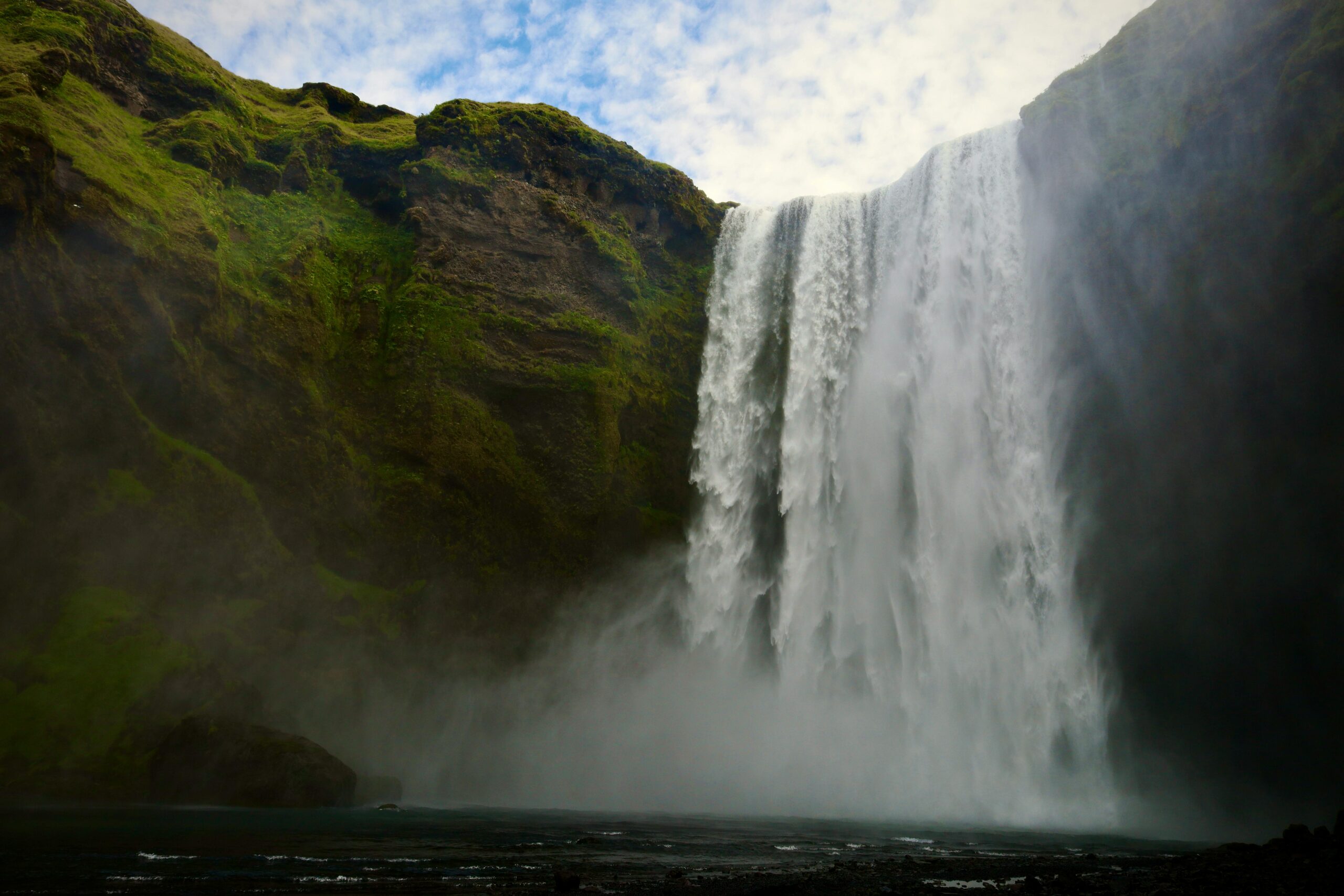 Breathtaking view of Skogafoss waterfall cascading into lush green cliffs in Iceland.