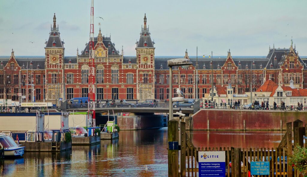 Scenic view of Amsterdam Centraal station and canal, capturing local architecture.