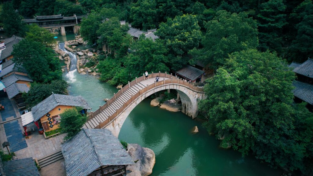 Aerial view of a historic stone bridge over a river surrounded by greenery in Jiangxi, China.