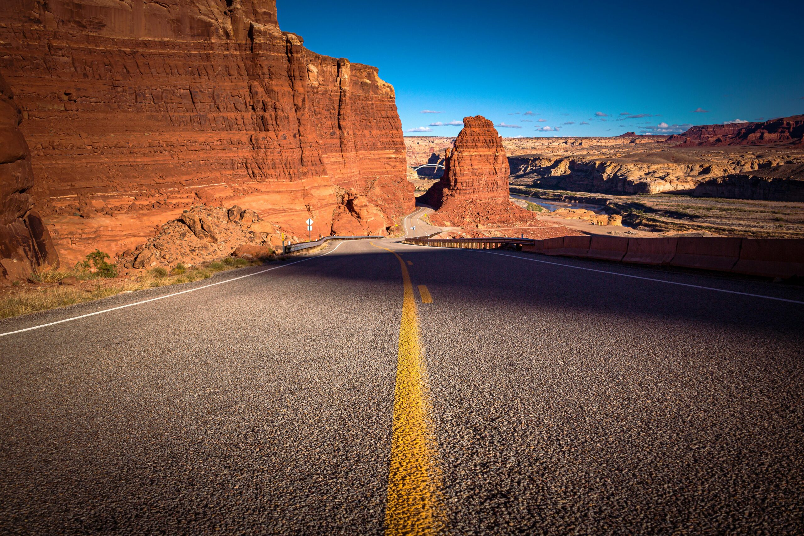 Experience the breathtaking view of a desert road cutting through Hite, Utah's stunning red rock canyons.