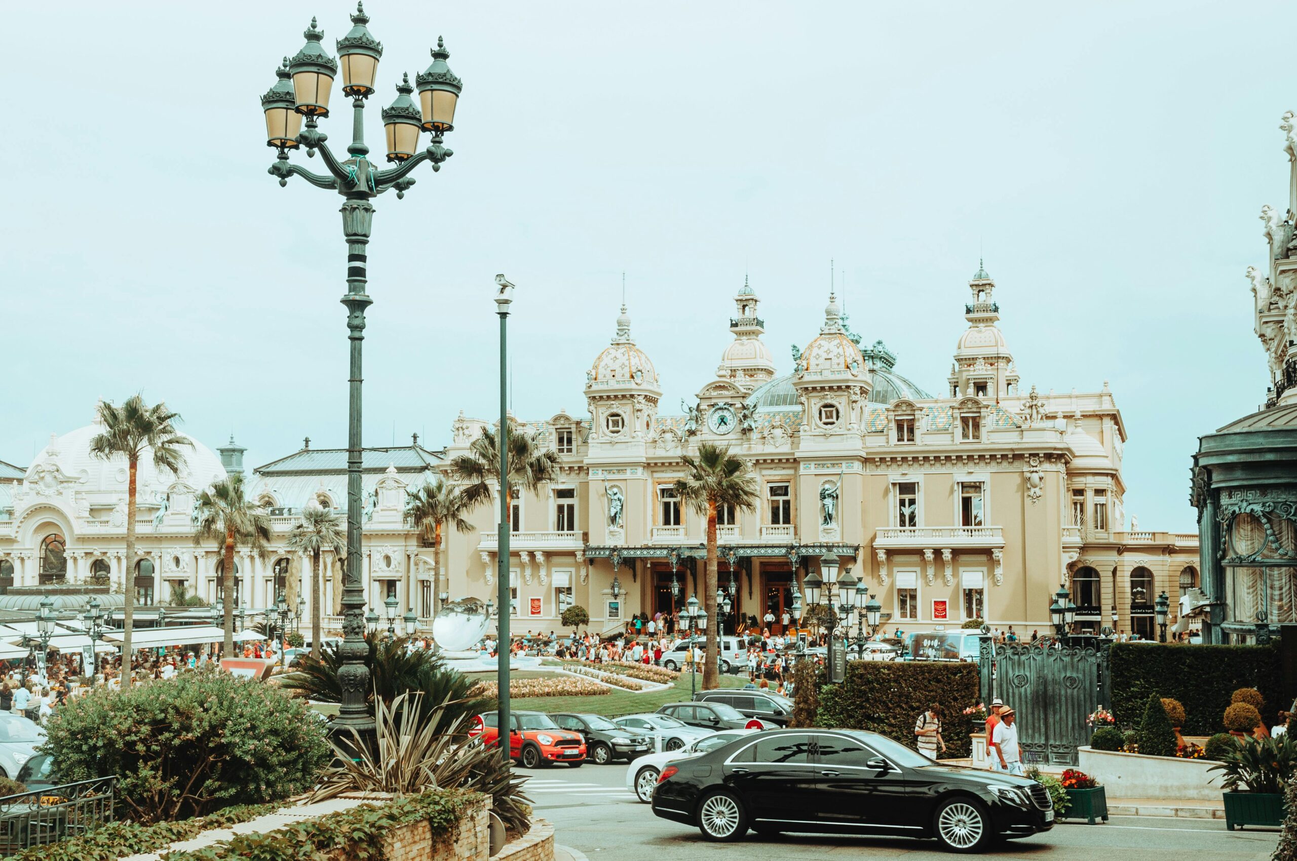 Classic view of Monte Carlo Casino with luxury cars and crowd. Iconic architecture in vibrant Monaco setting.