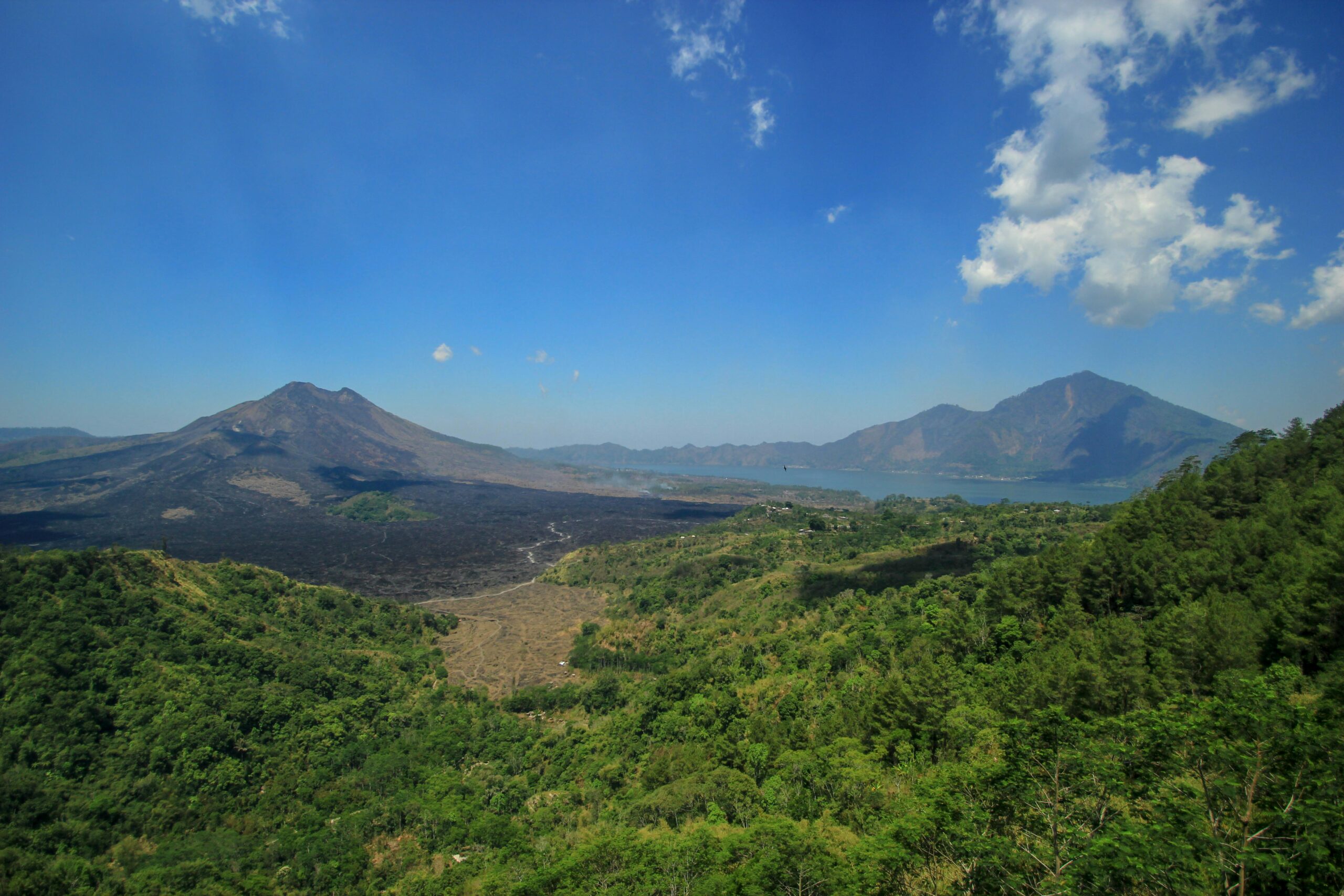 Breathtaking aerial view of Mount Batur and lush valley in Bali with clear blue skies.