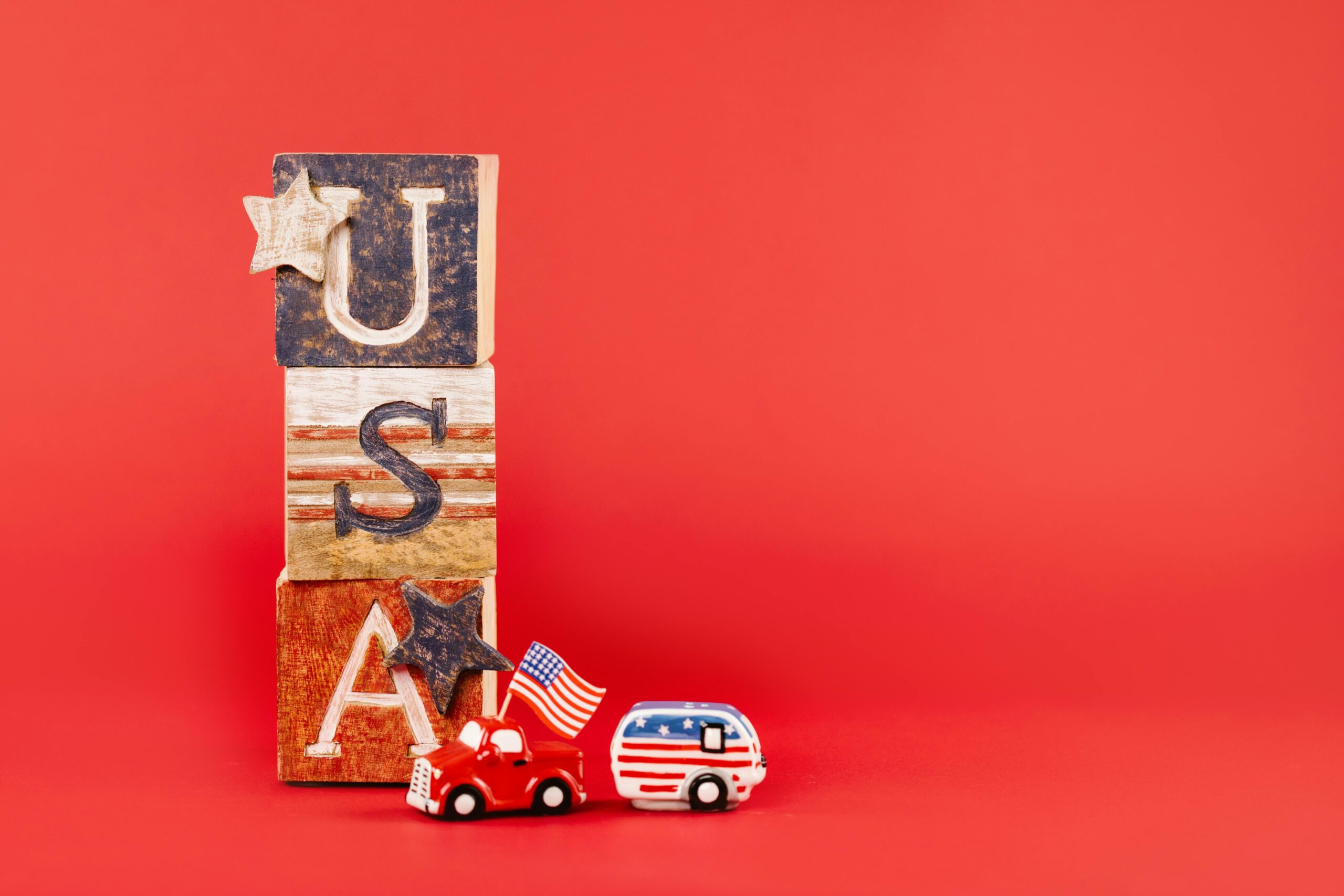 USA-themed wooden blocks and toy vehicles with flags on a red background.