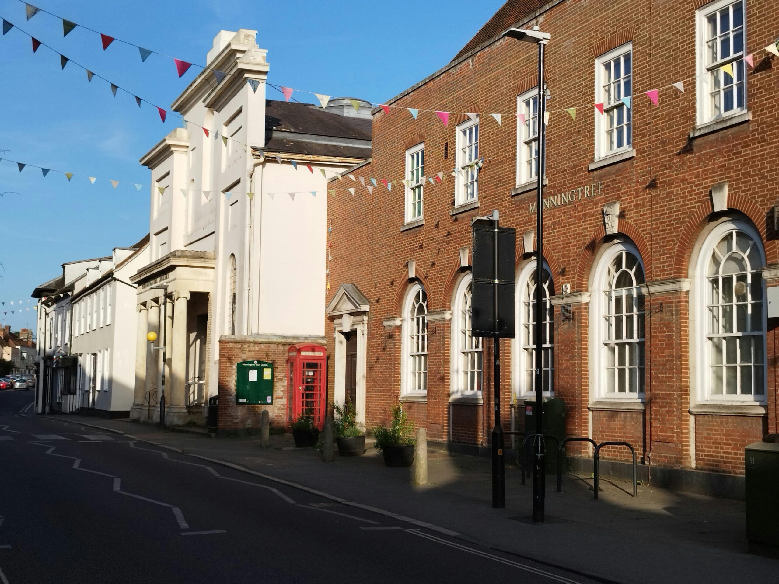 Picturesque street with red phone box in Manningtree, England on a sunny day.