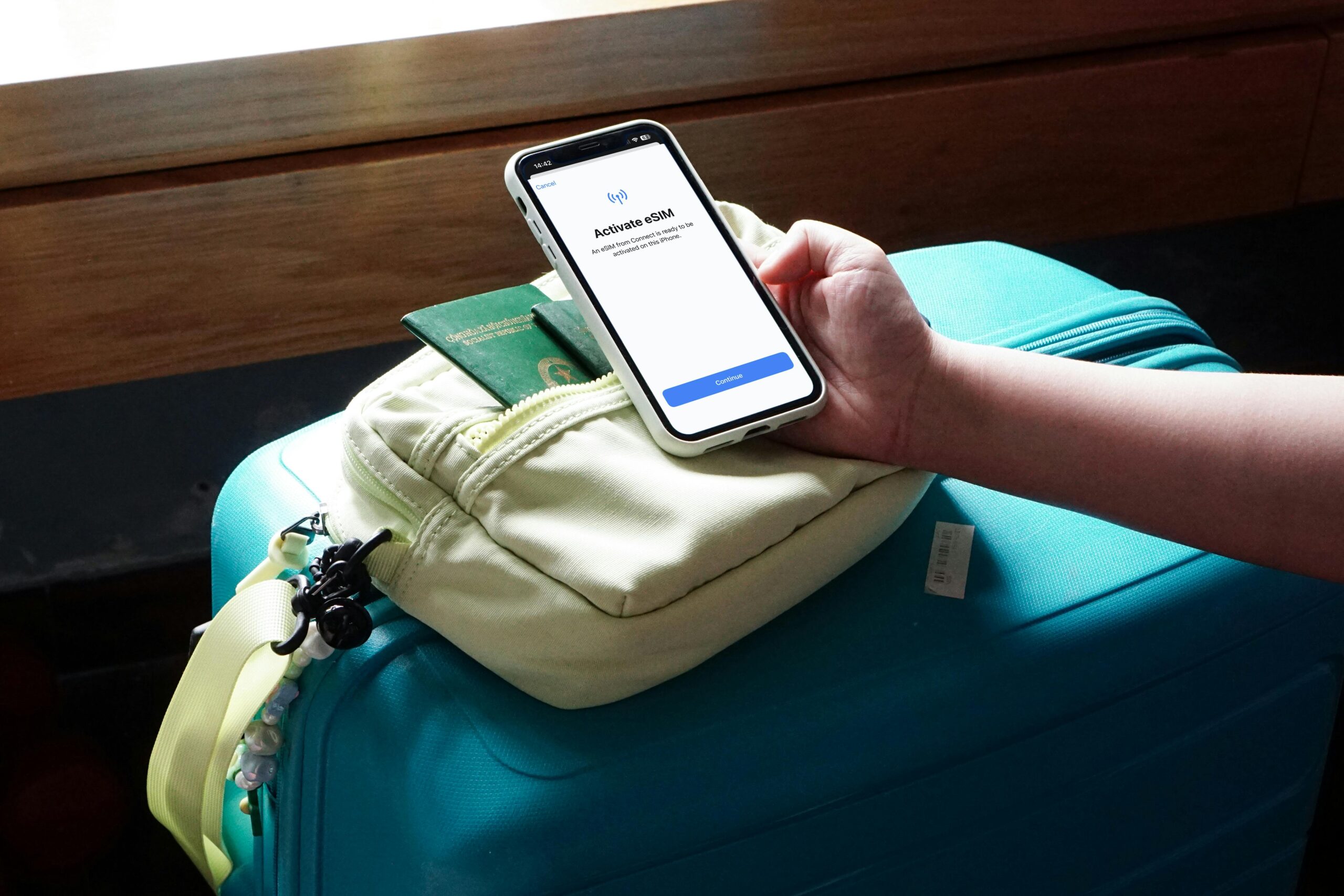 Close-up of a traveler activating eSIM on a smartphone over luggage, ready for a trip.