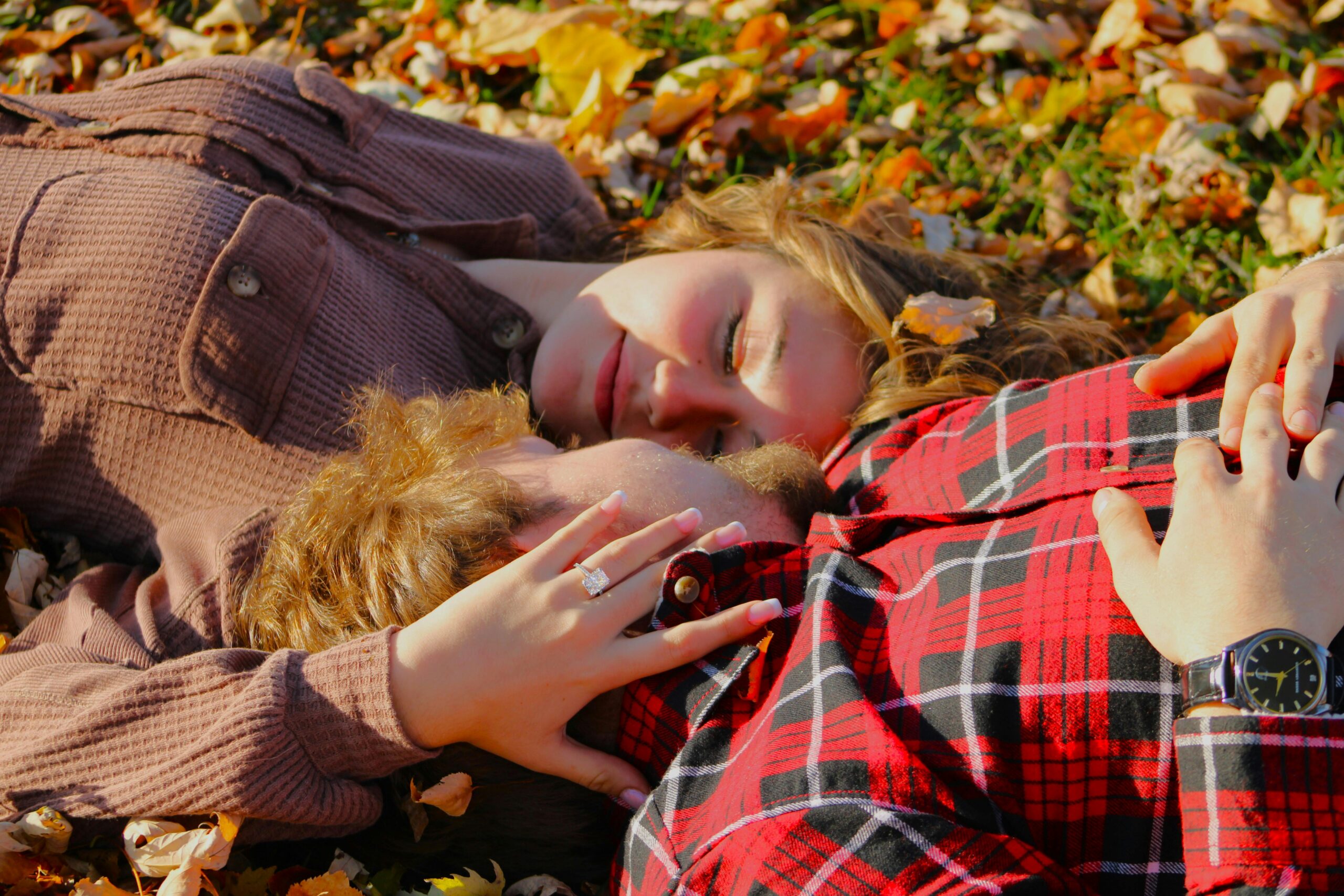 A loving couple embracing in a vibrant autumn setting, surrounded by colorful leaves, in Jackson, Michigan.