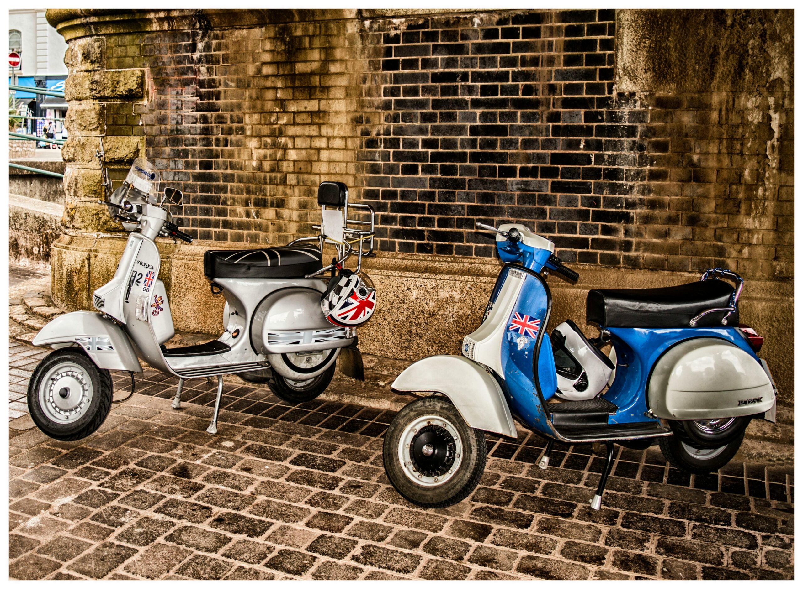 Classic scooters parked under an old brick archway in Devon, capturing a vintage urban style.