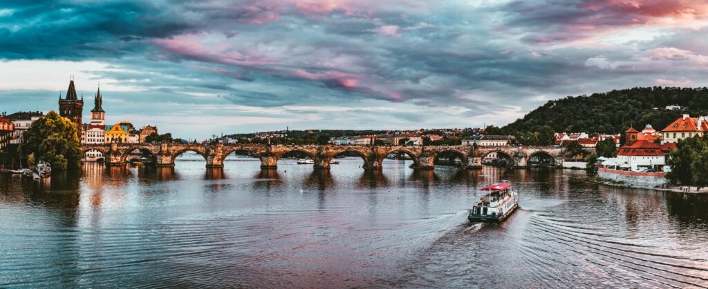 Stunning view of Charles Bridge with vibrant sunset hues over Vltava River in Prague.