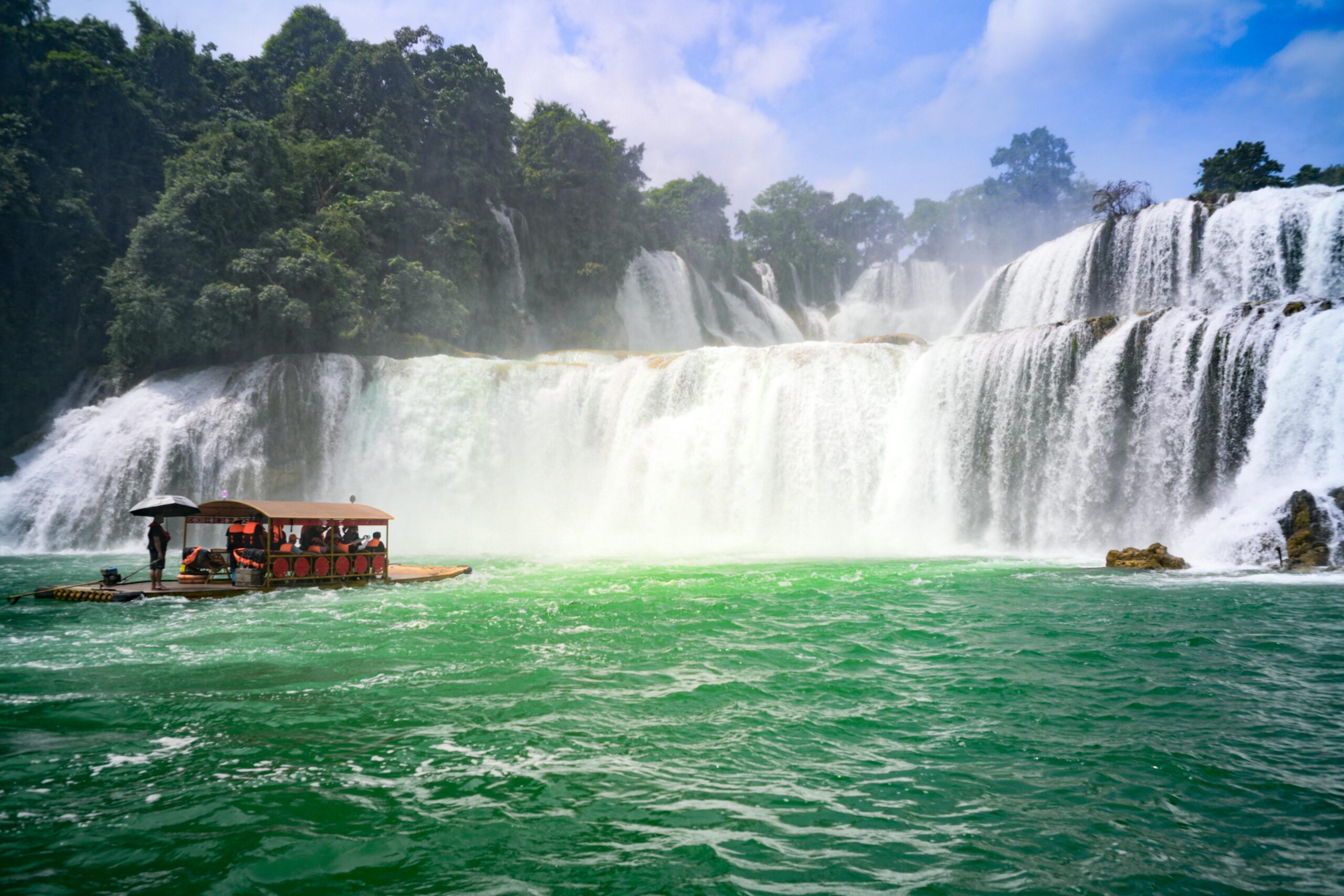 Picturesque view of Ban Gioc Waterfall with a traditional boat in Cao Bang, Vietnam.