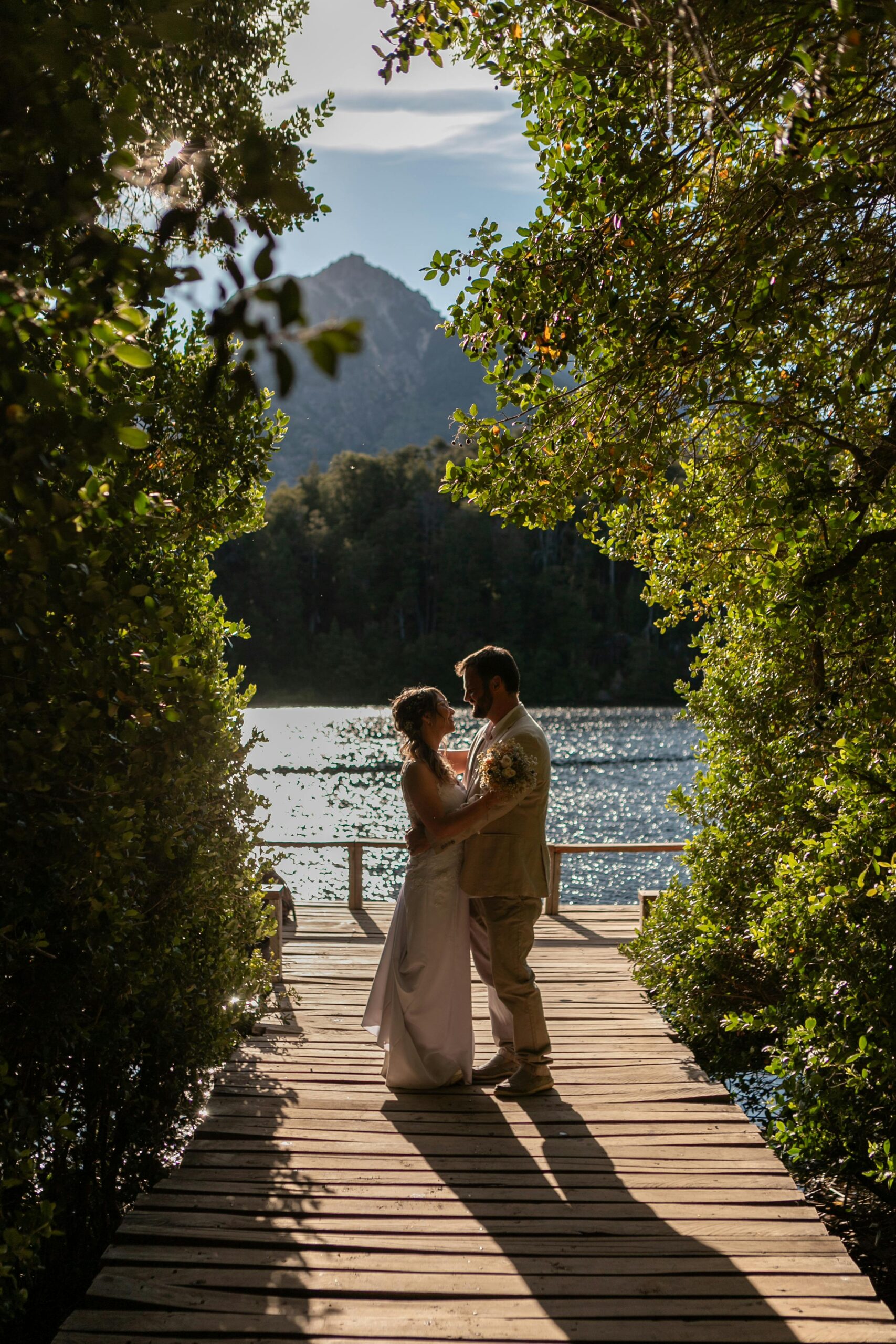 A couple embraces on a scenic pier surrounded by nature in Bariloche, Argentina.